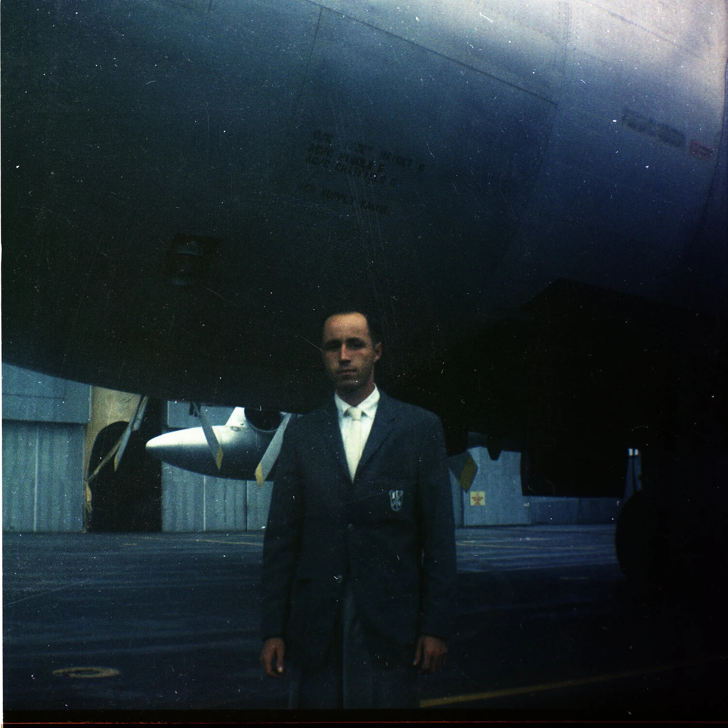 Crew Chief Nameplate Stencil Beneath USAF Aircraft Nose, with Airman Standing at Attention