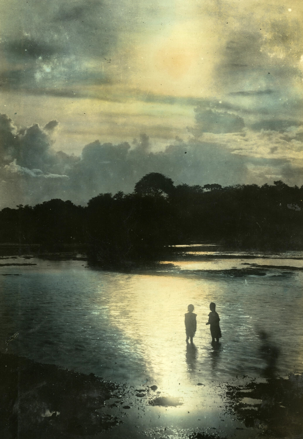 Two Children Silhouetted at Water's Edge Beneath a Dramatic Sky, Hand-Tinted Photograph, Philippines