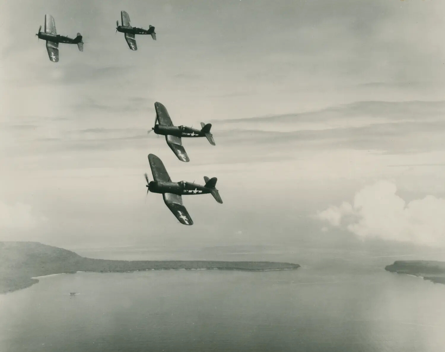 Formation of Four F4U Corsair Fighters Over Pacific Atoll, WWII