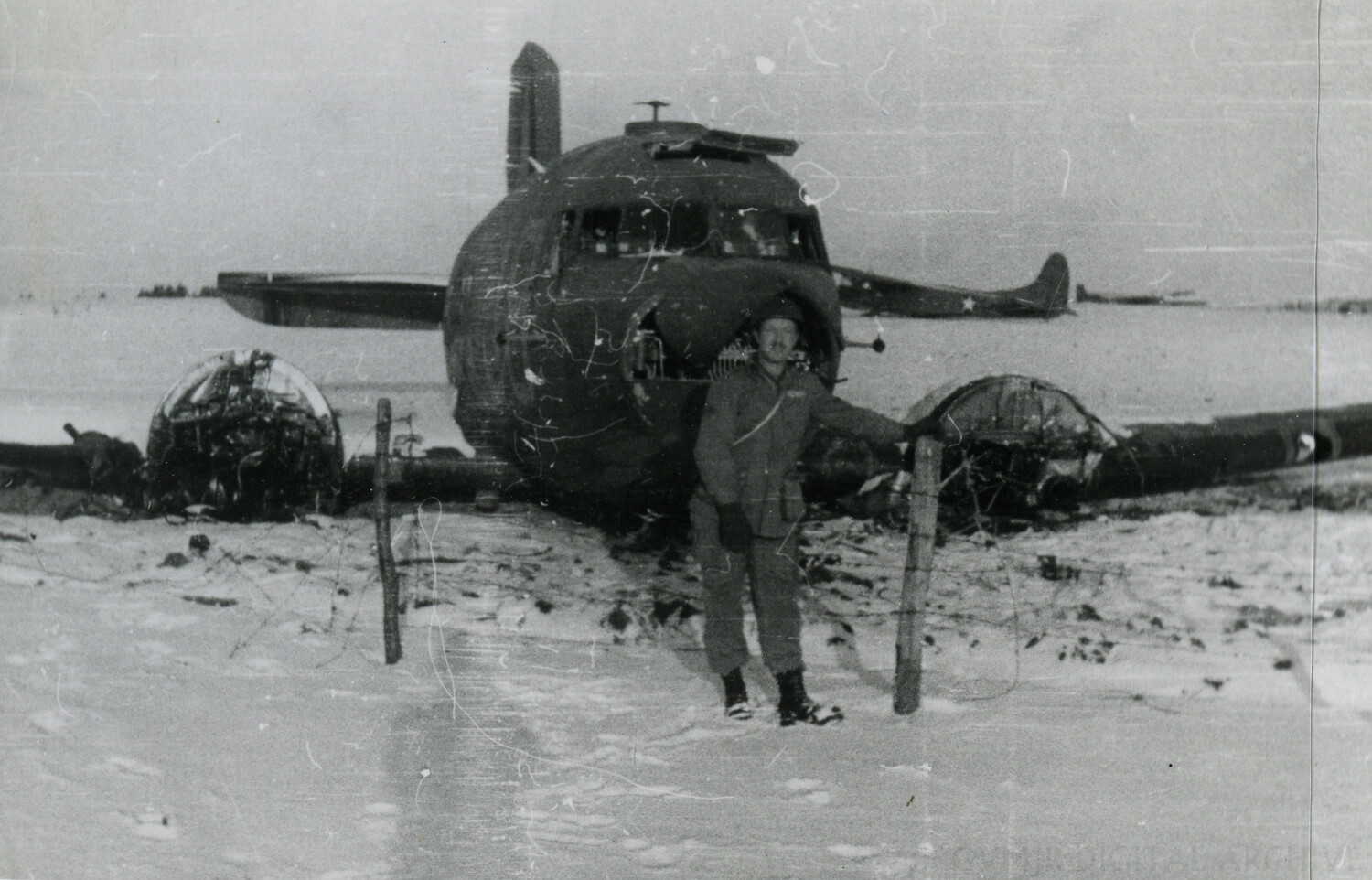 Soldier Posing Beside Wrecked Twin-Engine Bomber 'Ain't Missbehavin'', Winter 1944-1945 (Alternate View)