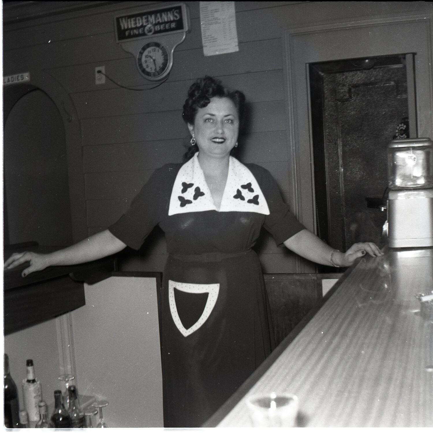 Barmaid Behind the Counter at a Tavern Advertising Wiedemann's Fine Beer, 1940s