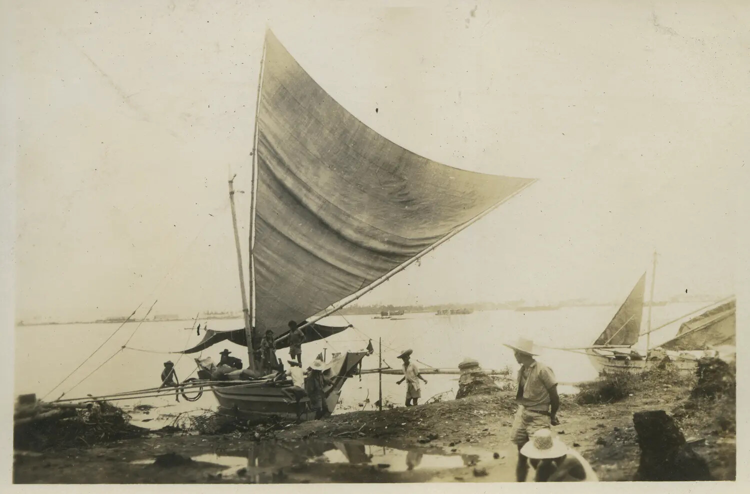 Native Outrigger Sailboat with Raised Sail on Beach