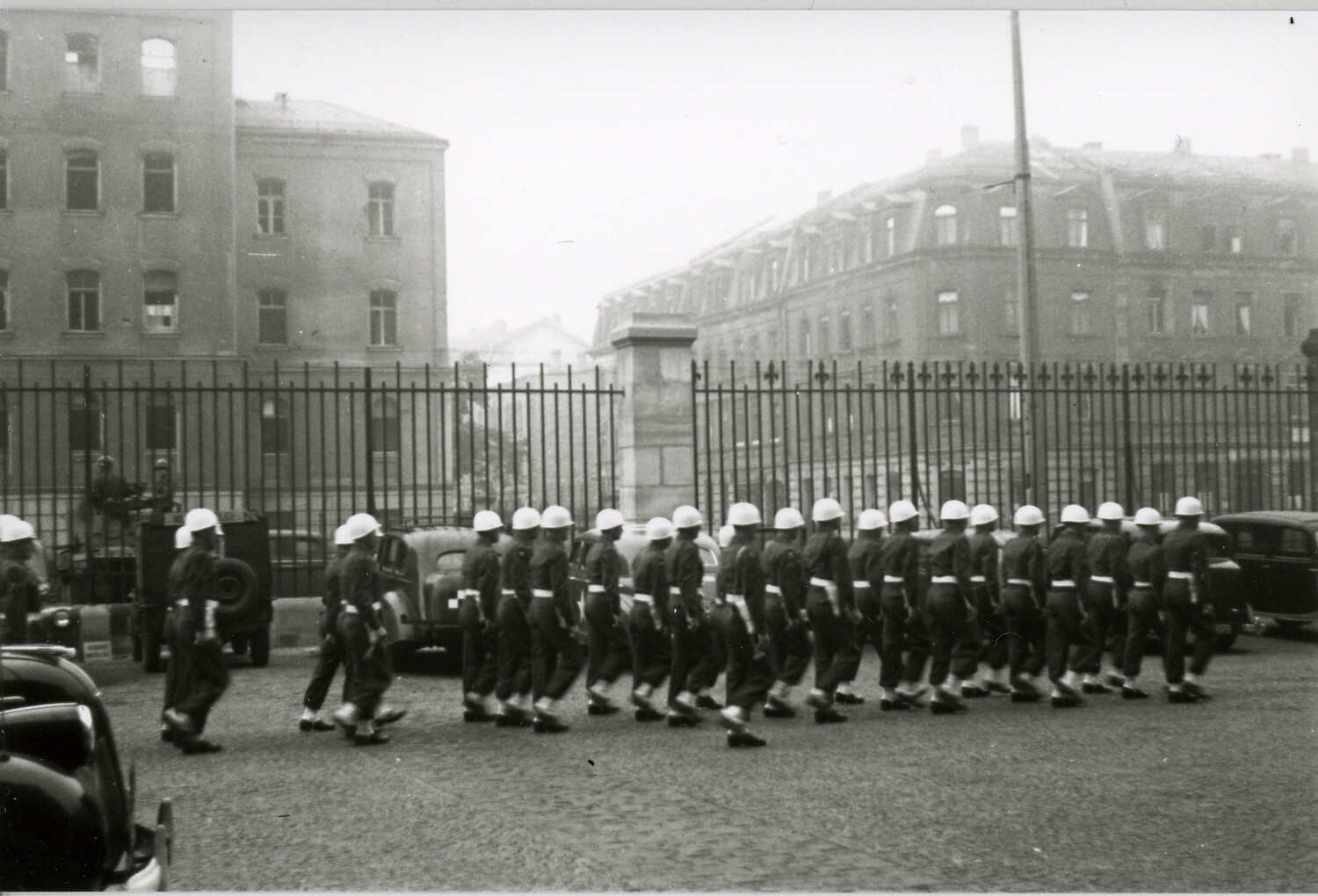 U.S. Military Police Column Marching Near War-Damaged Buildings, Likely Nuremberg, Germany, Post-WWII