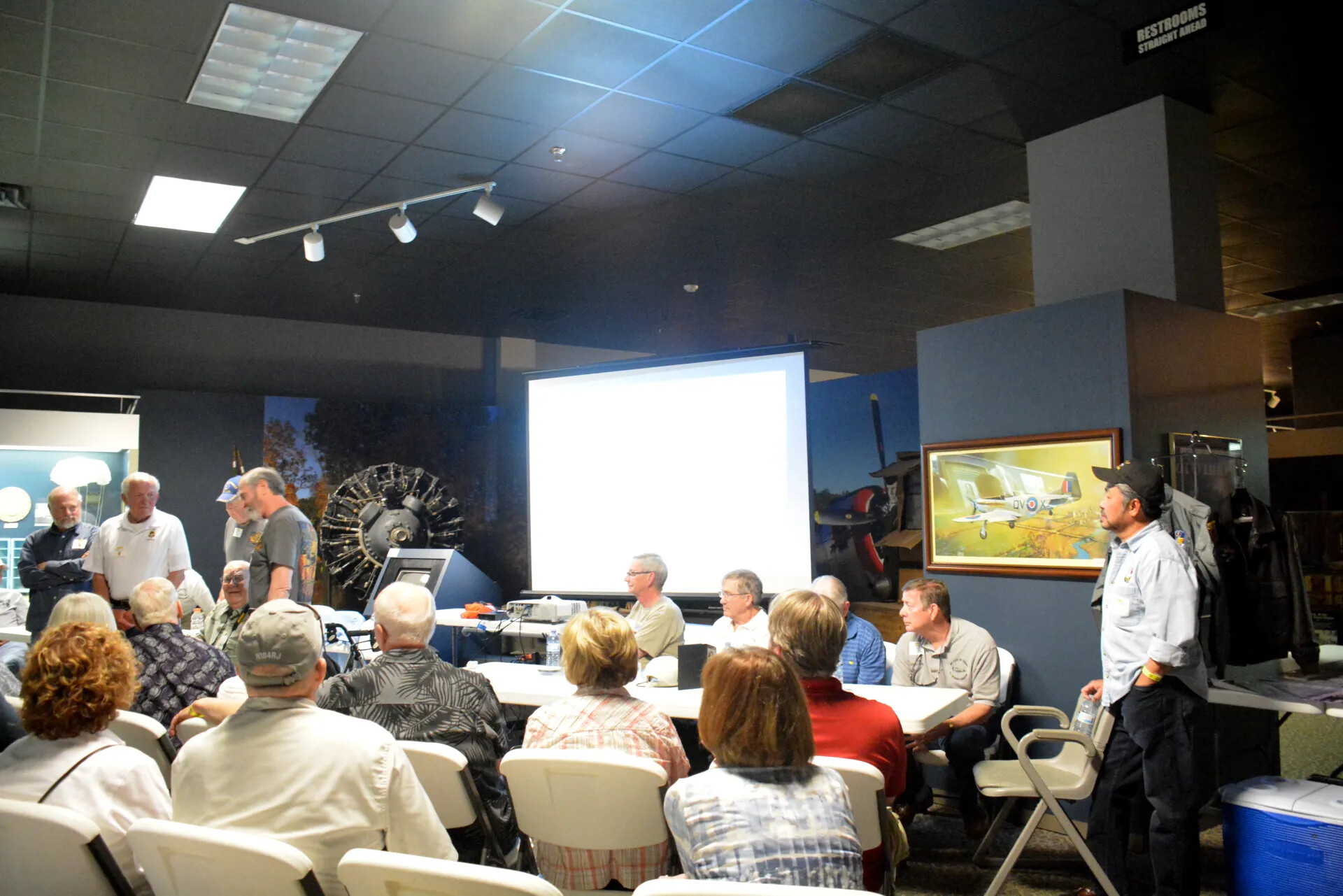 Veterans' Reunion Meeting, Aviation Museum — Group Assembled Near Screen with "N184RJ" Cap Visible