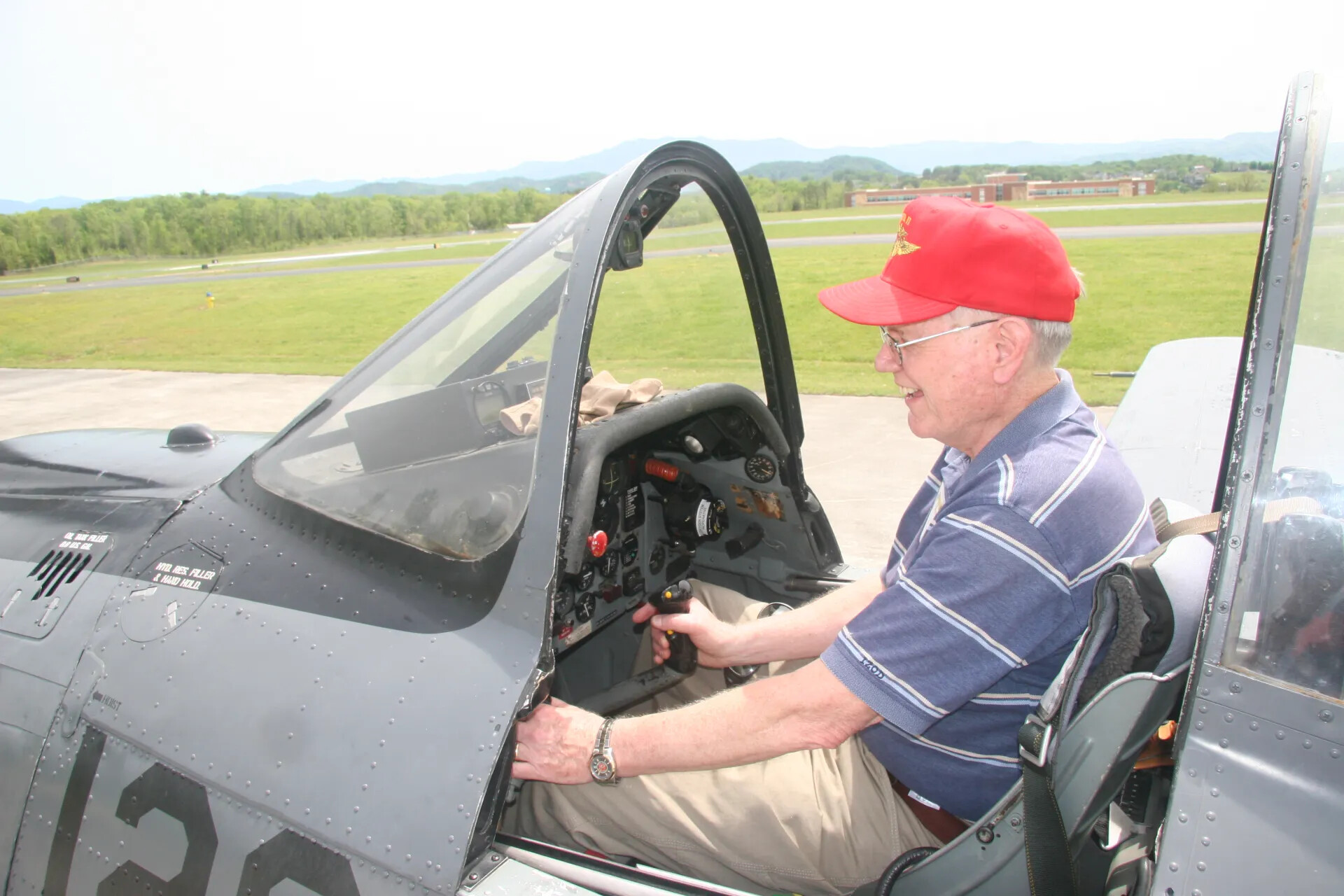 Attendee Seated in Cockpit of T-28-Type Trainer Aircraft, Hand on Control Stick