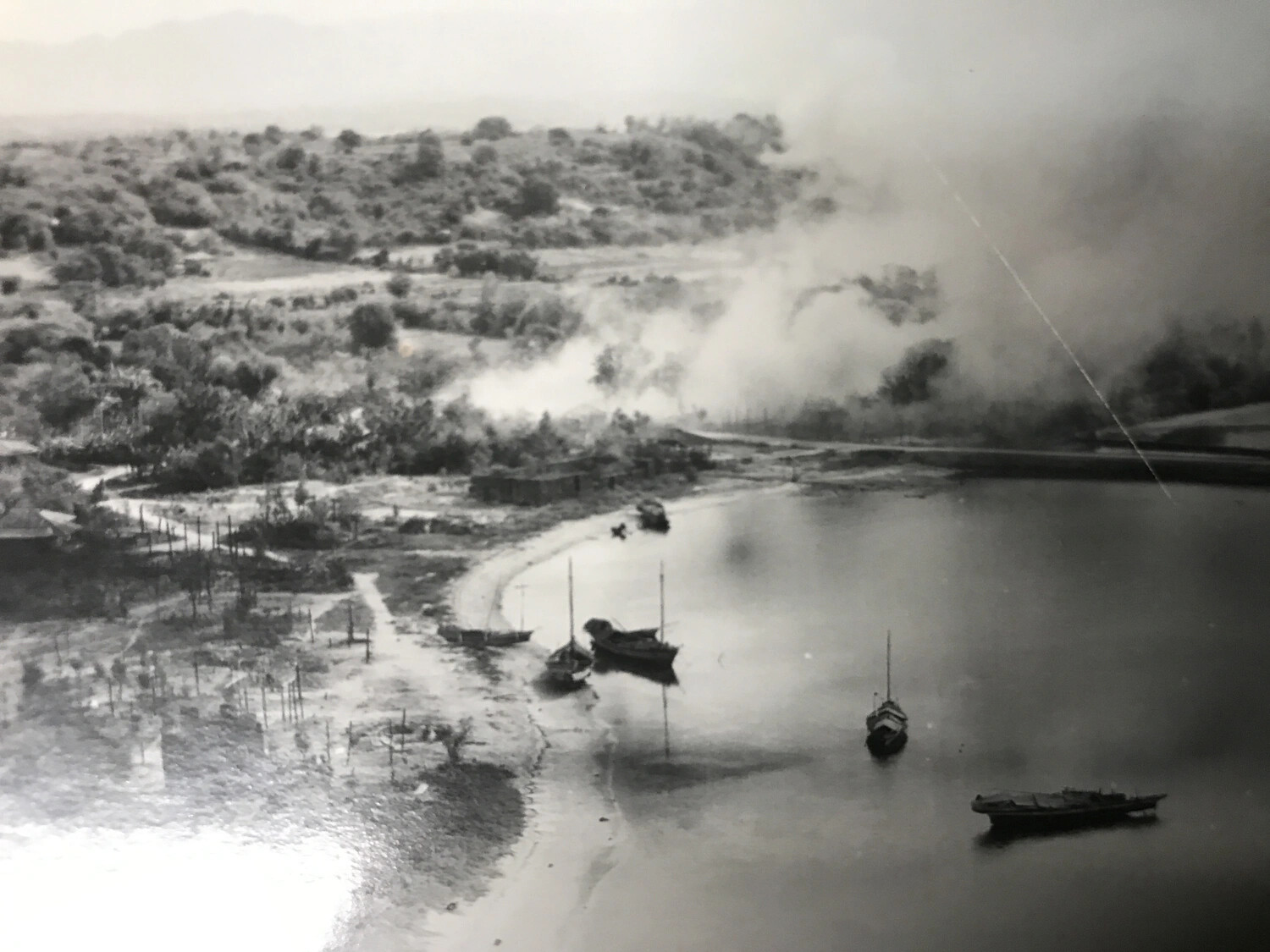 Aerial Photograph: Smoke Rising Over Coastal Bay with Moored Sailboats, Pacific Theater, WWII