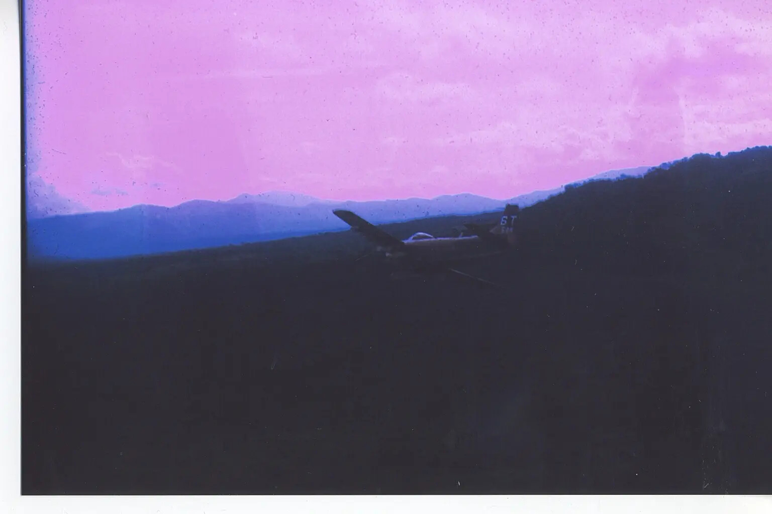 A-1 Skyraider "6T" in Flight at Dusk Over Mountain Ridgelines