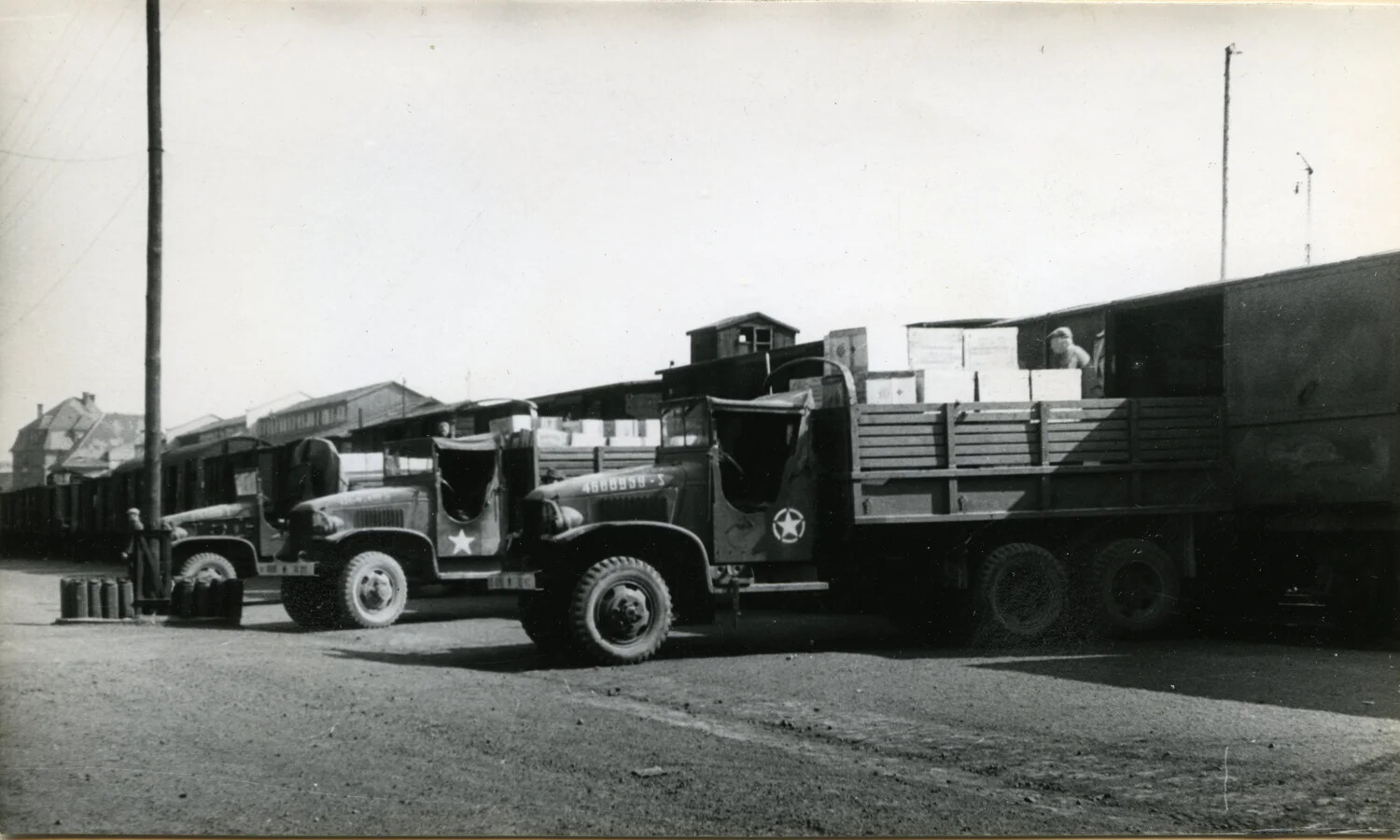 U.S. Army Cargo Trucks Unloading Supplies at Railhead, German Depot, Postwar Occupation Period (Detail View)