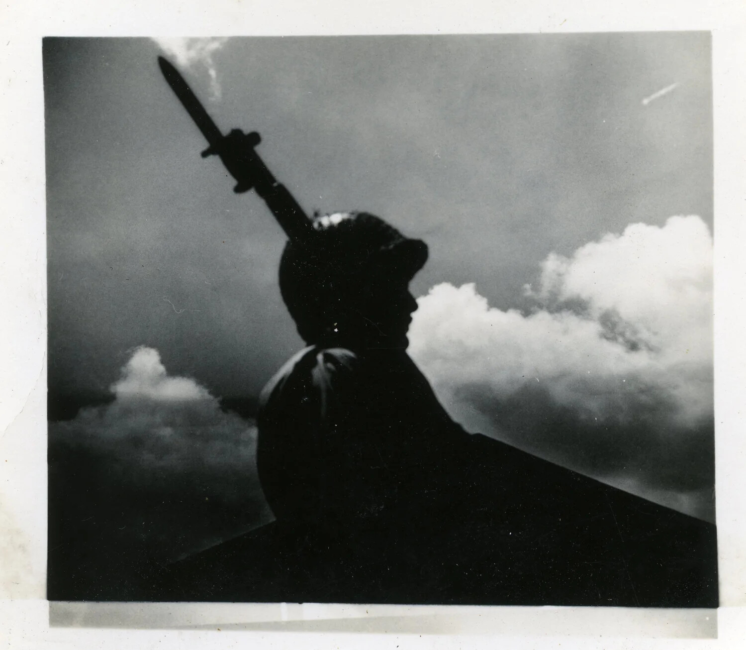 Close Silhouette of Helmeted Serviceman with Fixed Bayonet Against Clouds, World War II Era