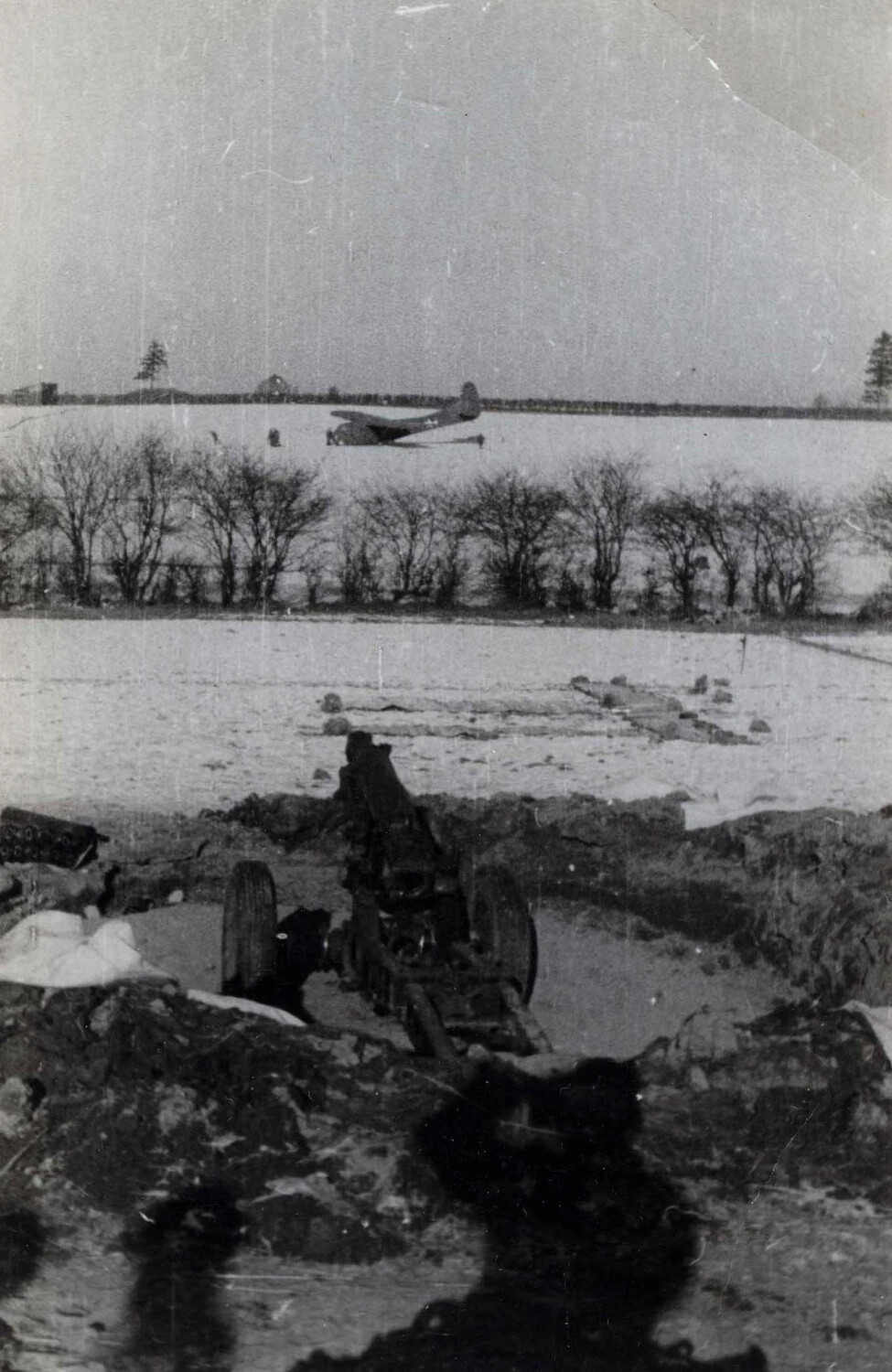 Artillery Piece in Muddy Gun Pit with Crash-Landed Glider in Background, Winter 1944-1945