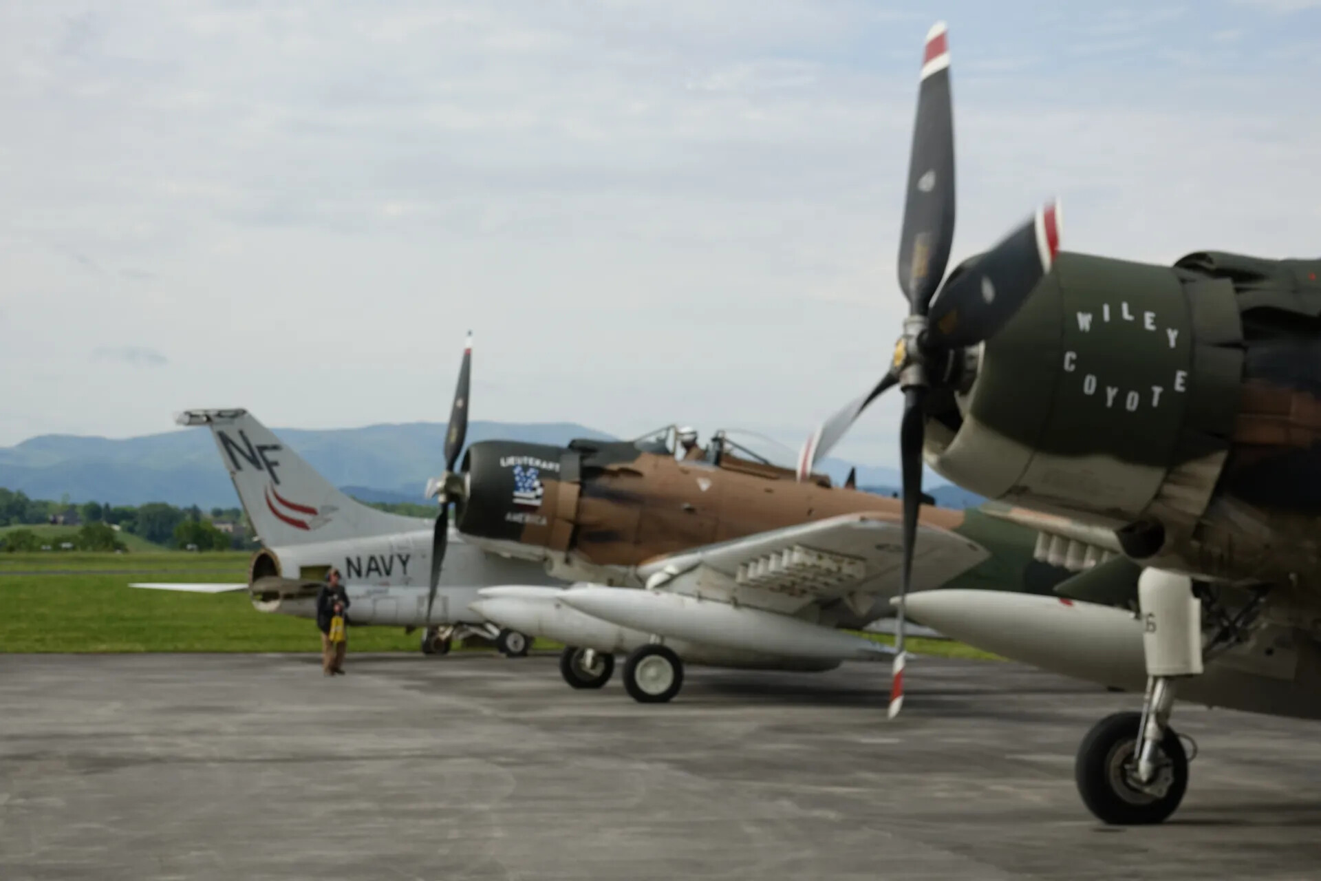 A-7 Corsair II and Two A-1 Skyraiders on Ramp, Mountain Backdrop