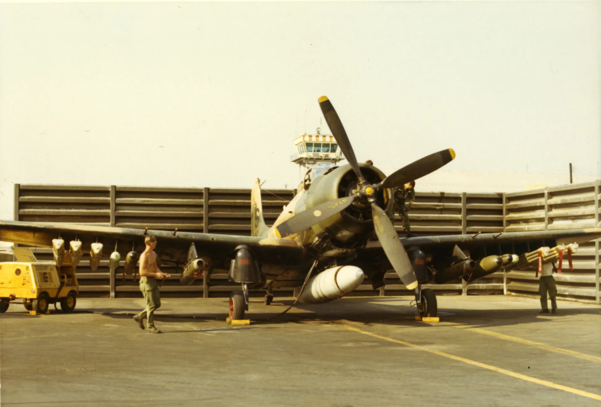 Camouflaged A-1 Skyraider Serviced on Ramp with Control Tower in Background, Vietnam War