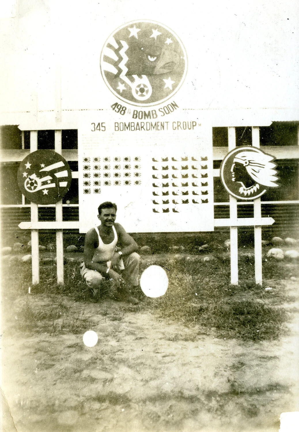 Airman Posed Before 498th Bombardment Squadron, 345th Bombardment Group Unit Sign and Mission Tally Board