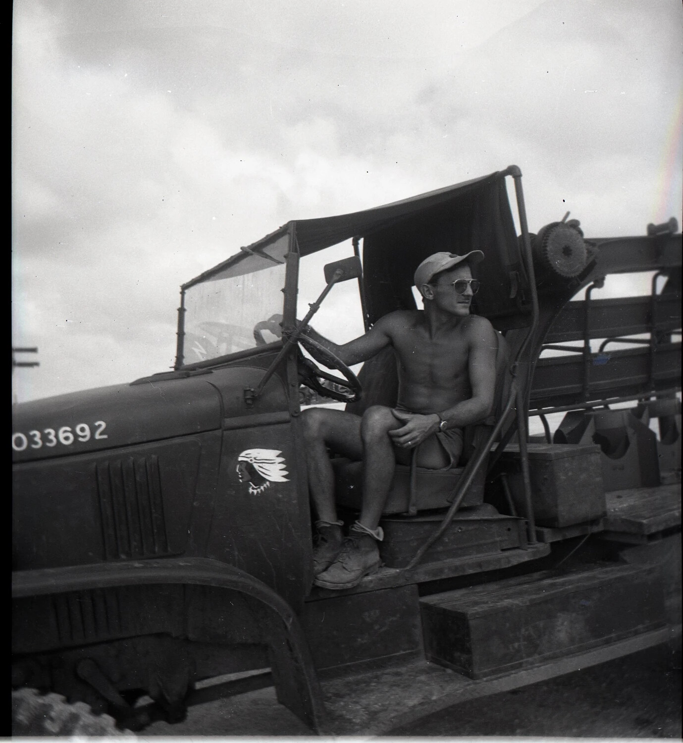 Serviceman at the Wheel of an Army Cargo Truck with Painted Indian-Head Emblem
