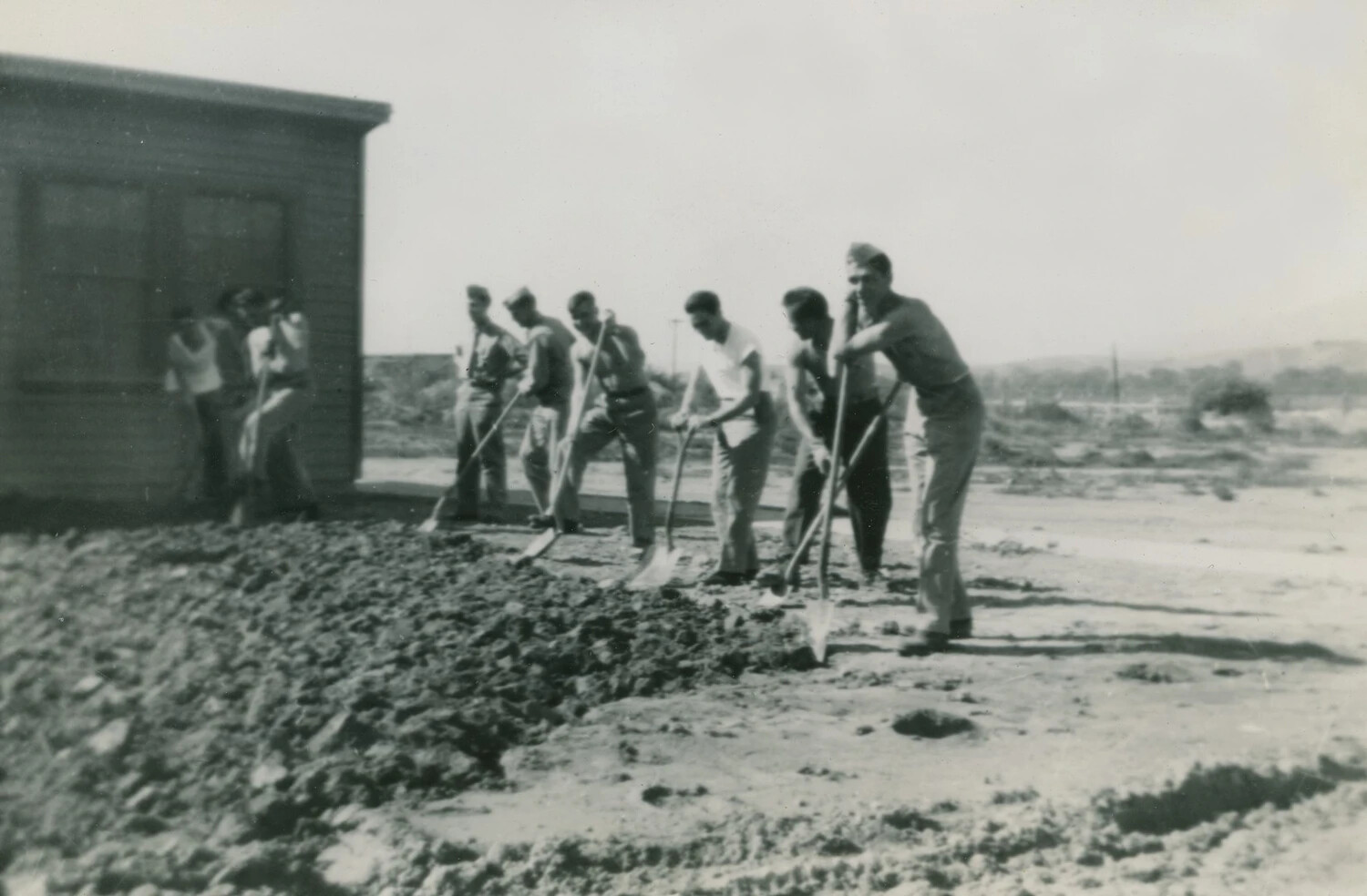 Servicemen Shoveling Earth Near Wooden Building