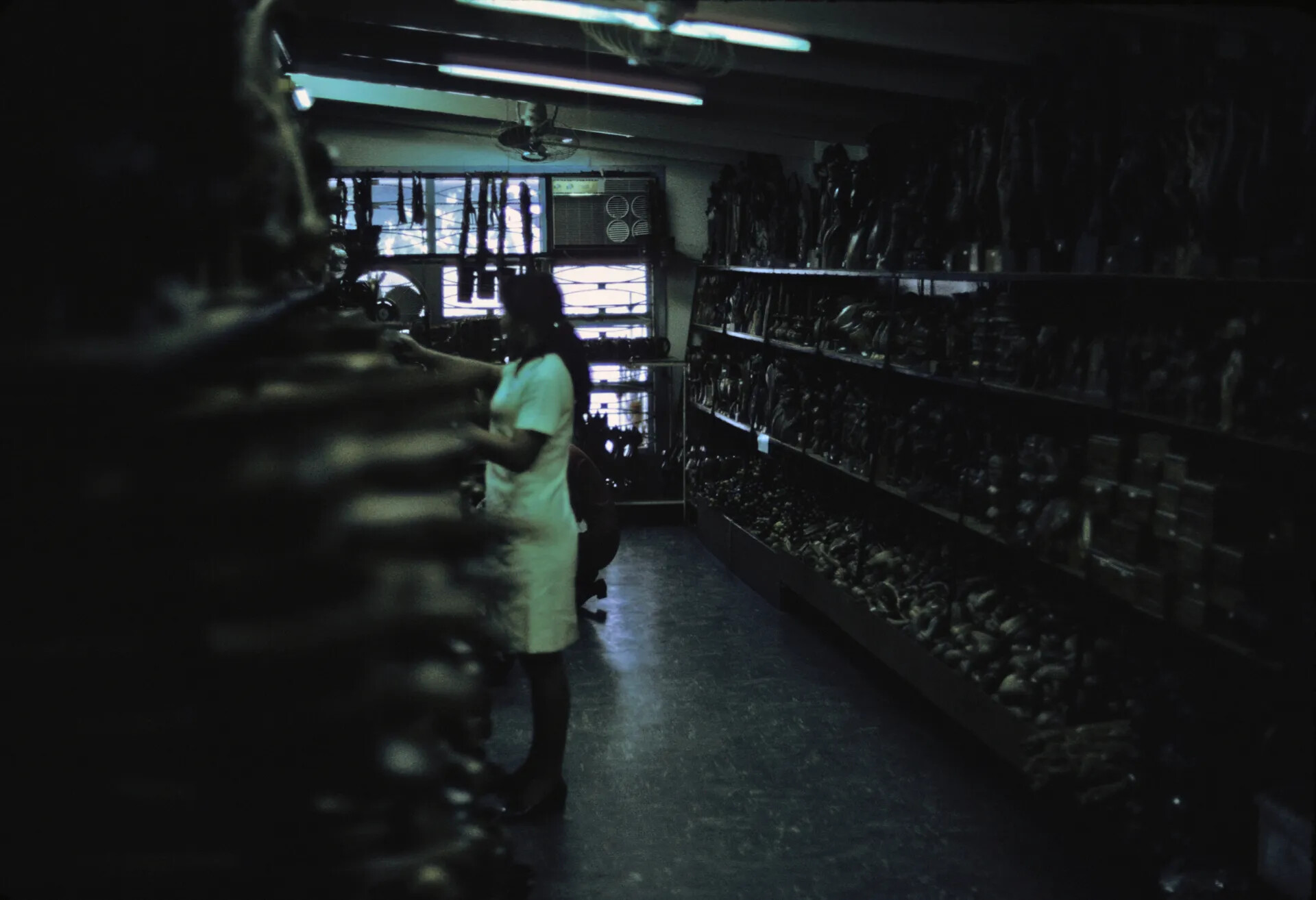 Woman Browsing Carved Wood Curios in Souvenir Shop, Southeast Asia, 1969
