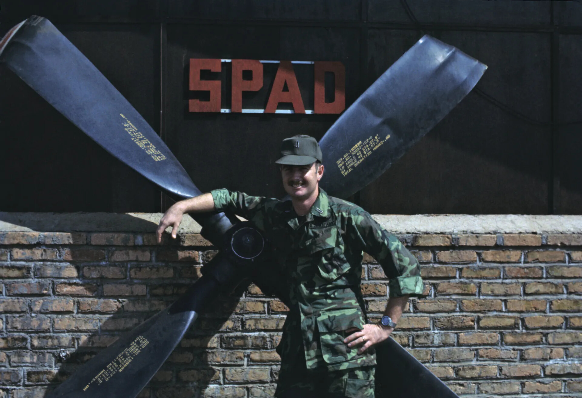 U.S. Air Force Officer Posing with Propeller Display Beneath "SPAD" Sign