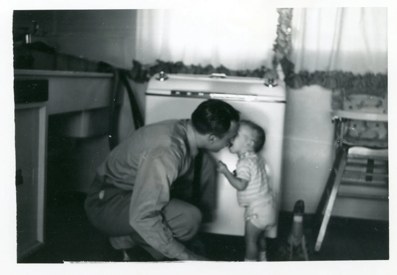 Serviceman Greeting Young Child in Home Kitchen — Korean War-Era Family Snapshot