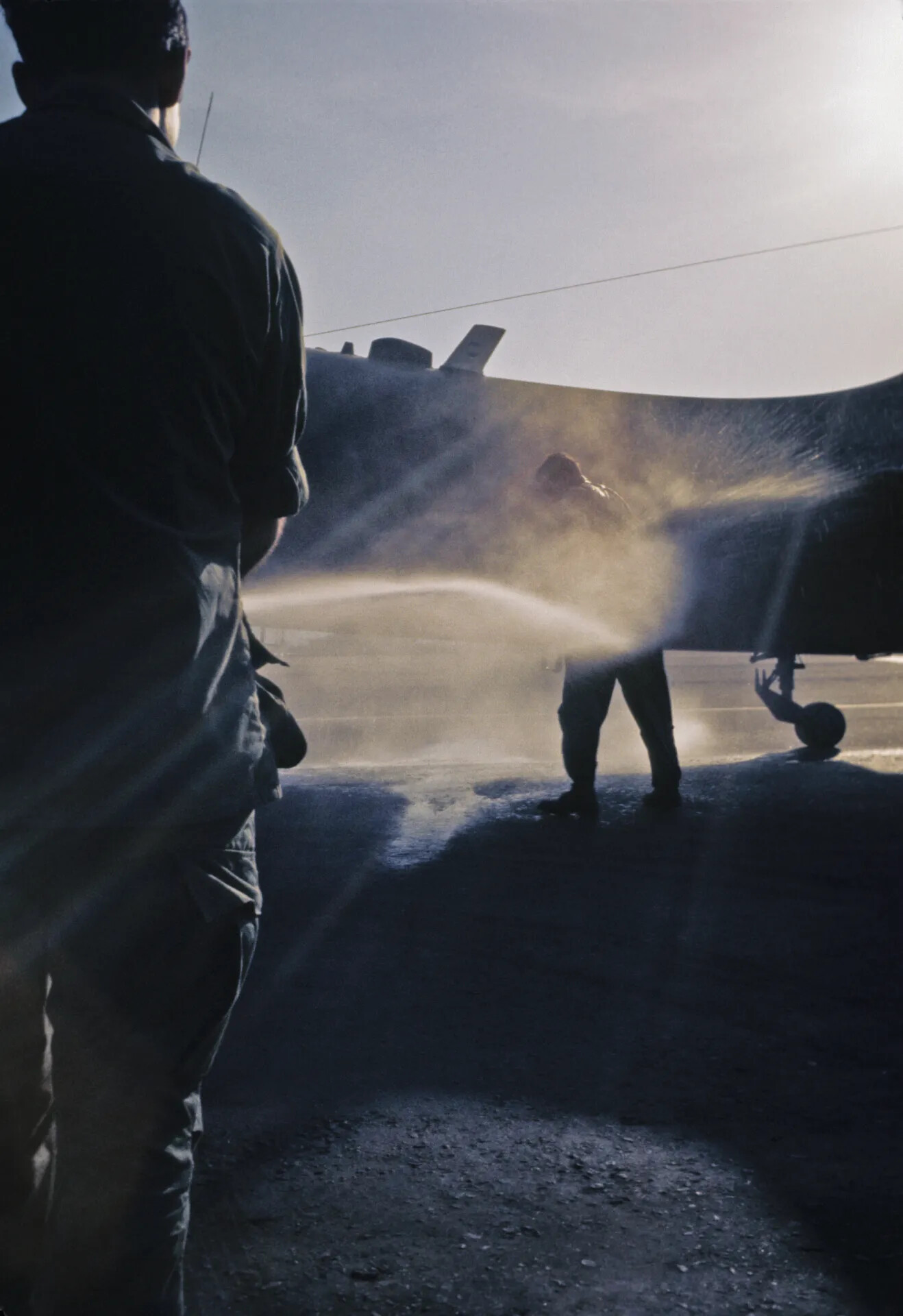 Ground Crew Washing Down an A-1 Skyraider, Backlit Flight Line Scene