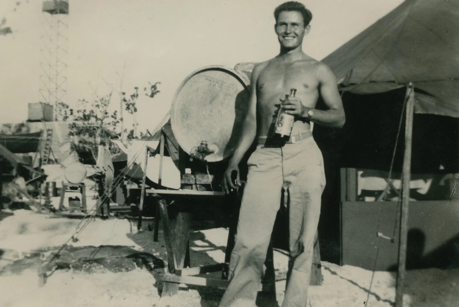 Serviceman at Pacific Island Camp with Water Barrel and Tent, WWII - McAleer Collection