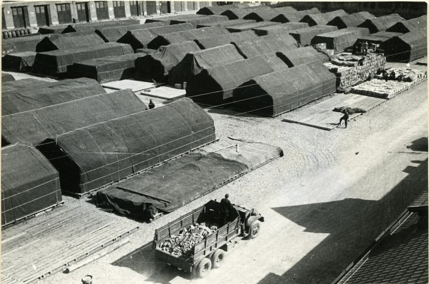 Elevated View of Tarpaulin-Covered Storage Stacks and Cargo Truck, U.S. Military Supply Depot, Germany