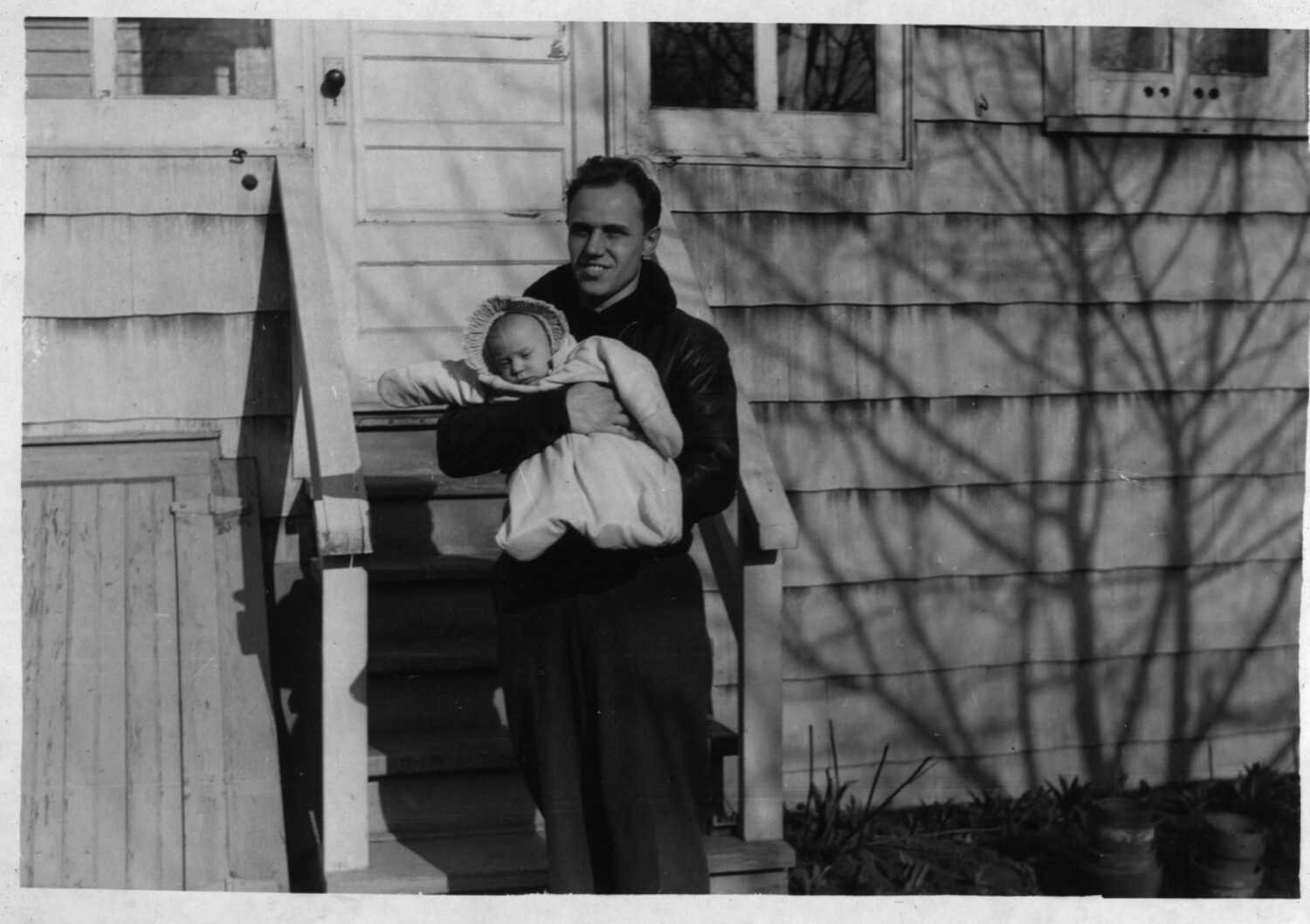 Naval Officer Holding Infant Outside Family Home, Korean War Era - Bancroft Collection