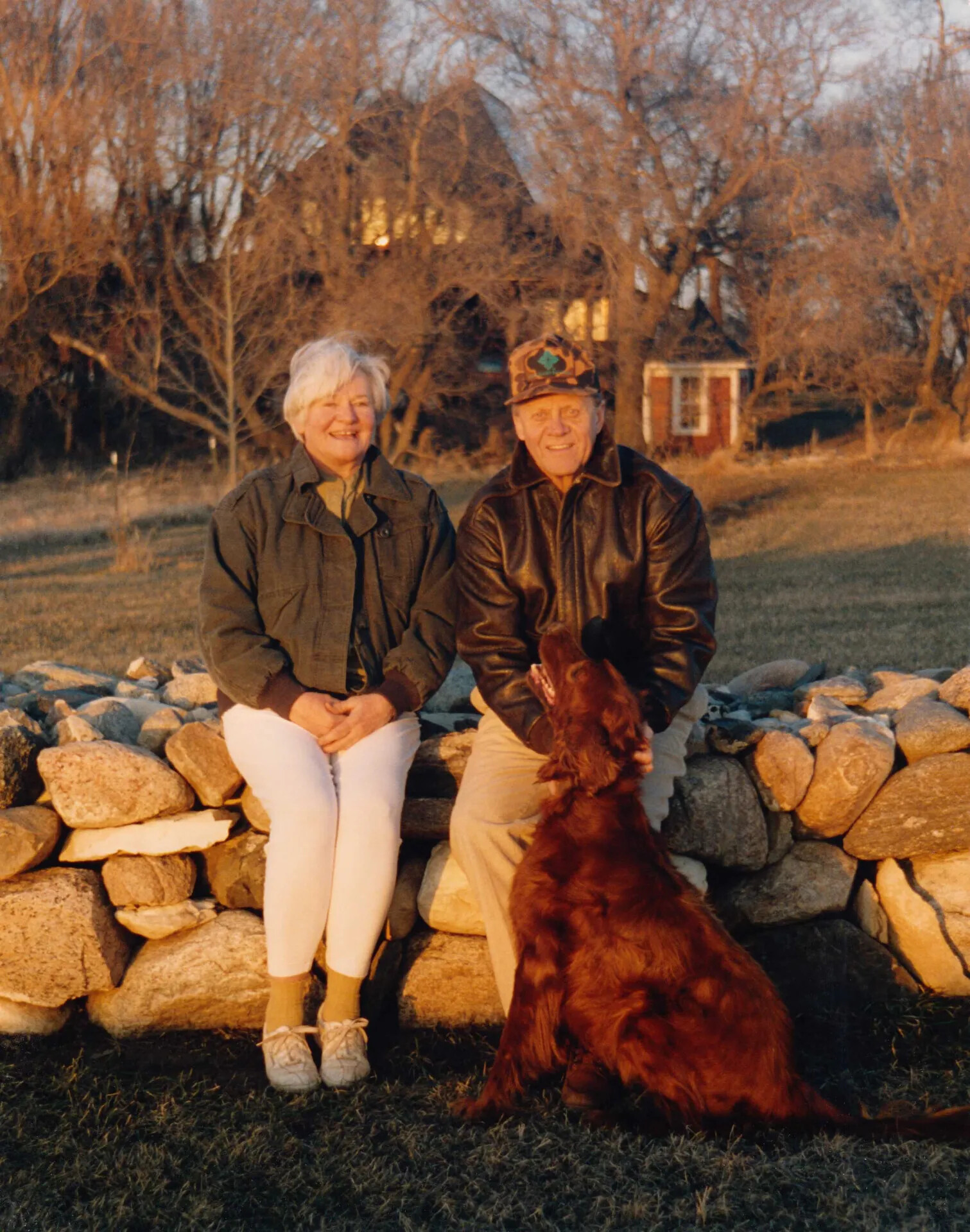 Jim and Joanne Wold Seated on Stone Wall with Family Dog, Rural Homestead