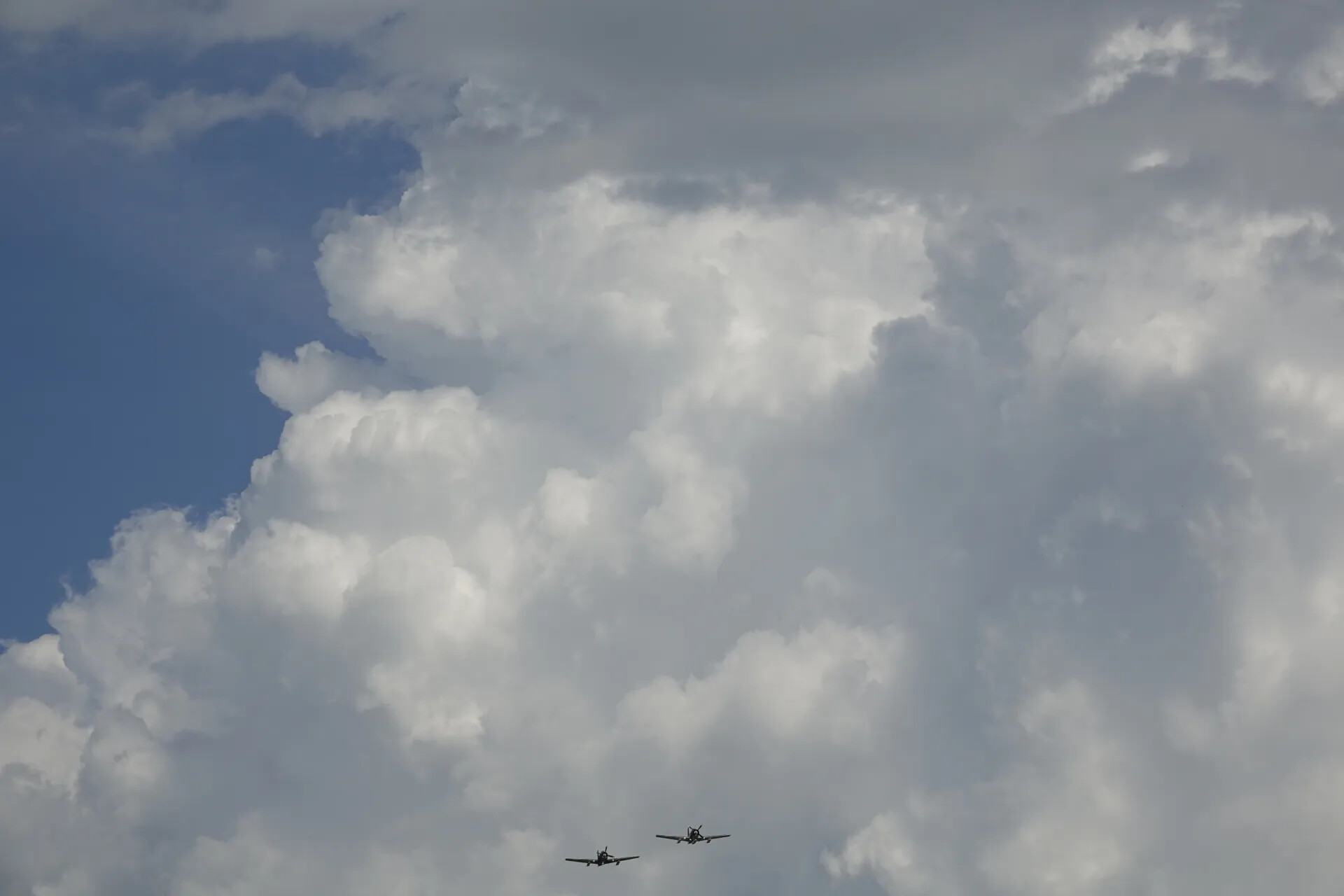 Two Propeller Aircraft in Formation Flight Against Cumulus Clouds