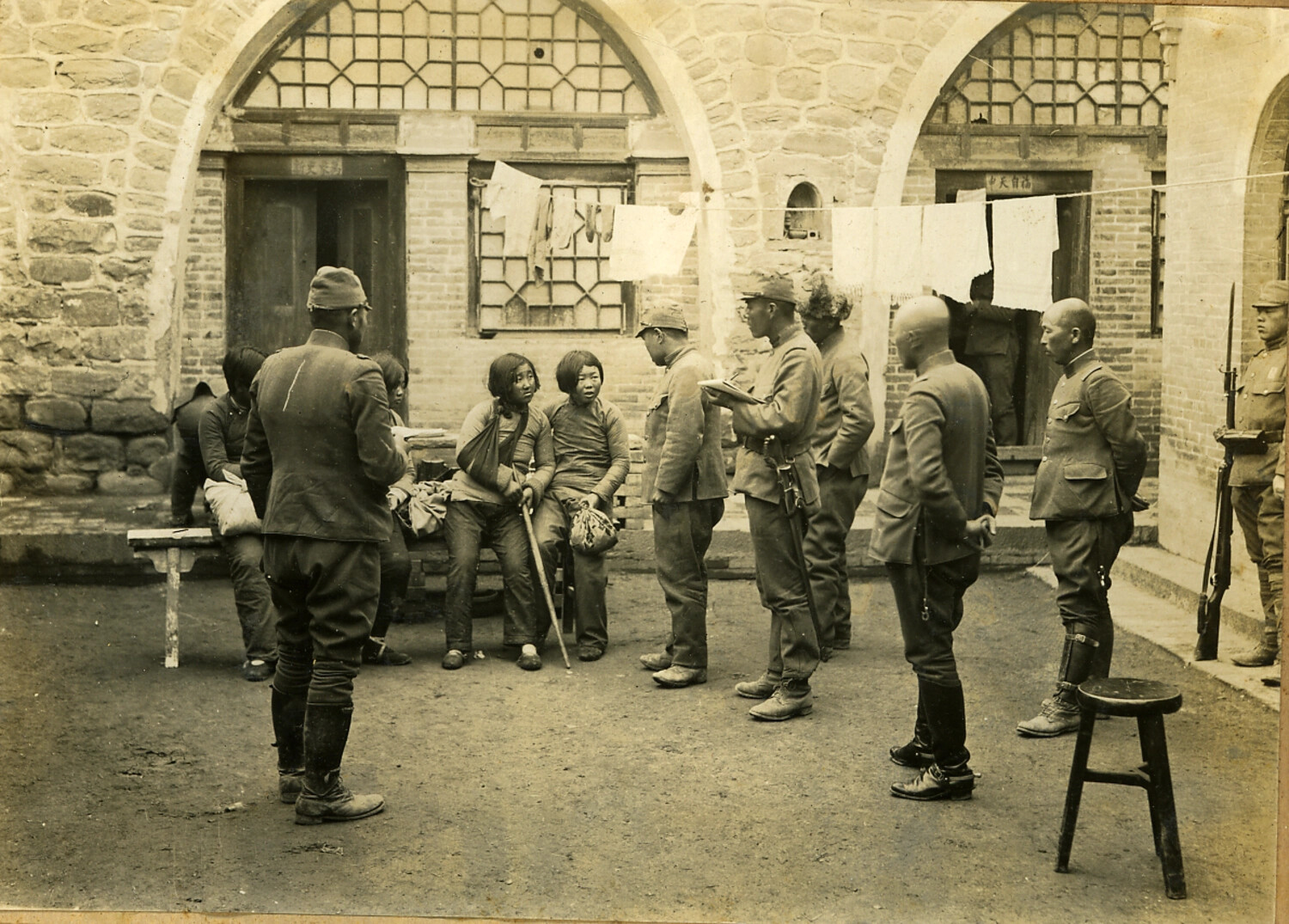 Japanese Army Personnel Questioning Local Civilians in Occupied Courtyard, China, WWII Era