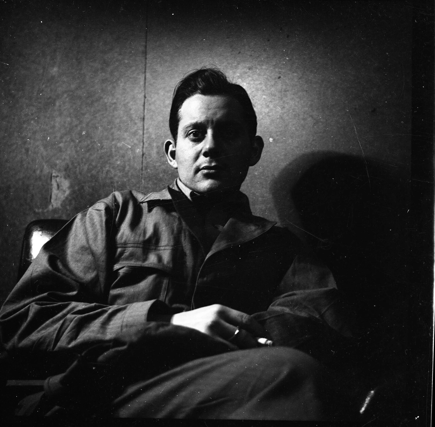 Candid Seated Portrait of a Man in Work Jacket with Cigarette, Dramatic Side Lighting