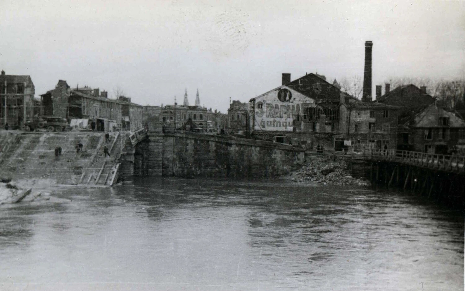 War-Damaged River Town with St Raphael Advertisement, Likely France, WWII Era