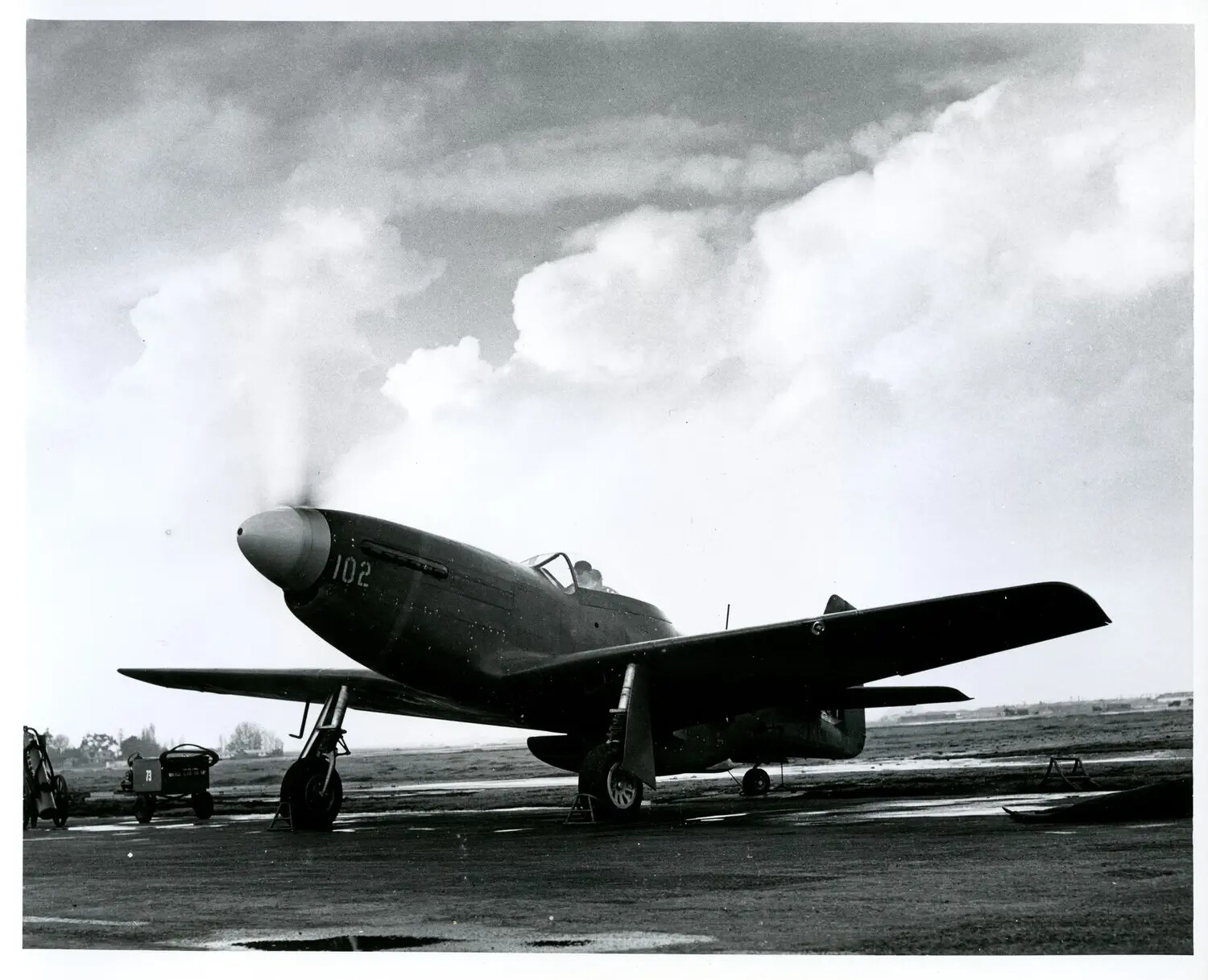 Single-Engine Fighter Aircraft with Engine Smoke on Ramp, Marked '102'