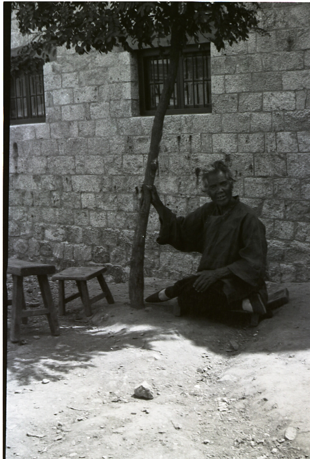 Elderly Man Seated Against a Stone Wall, China, Early-to-Mid 20th Century
