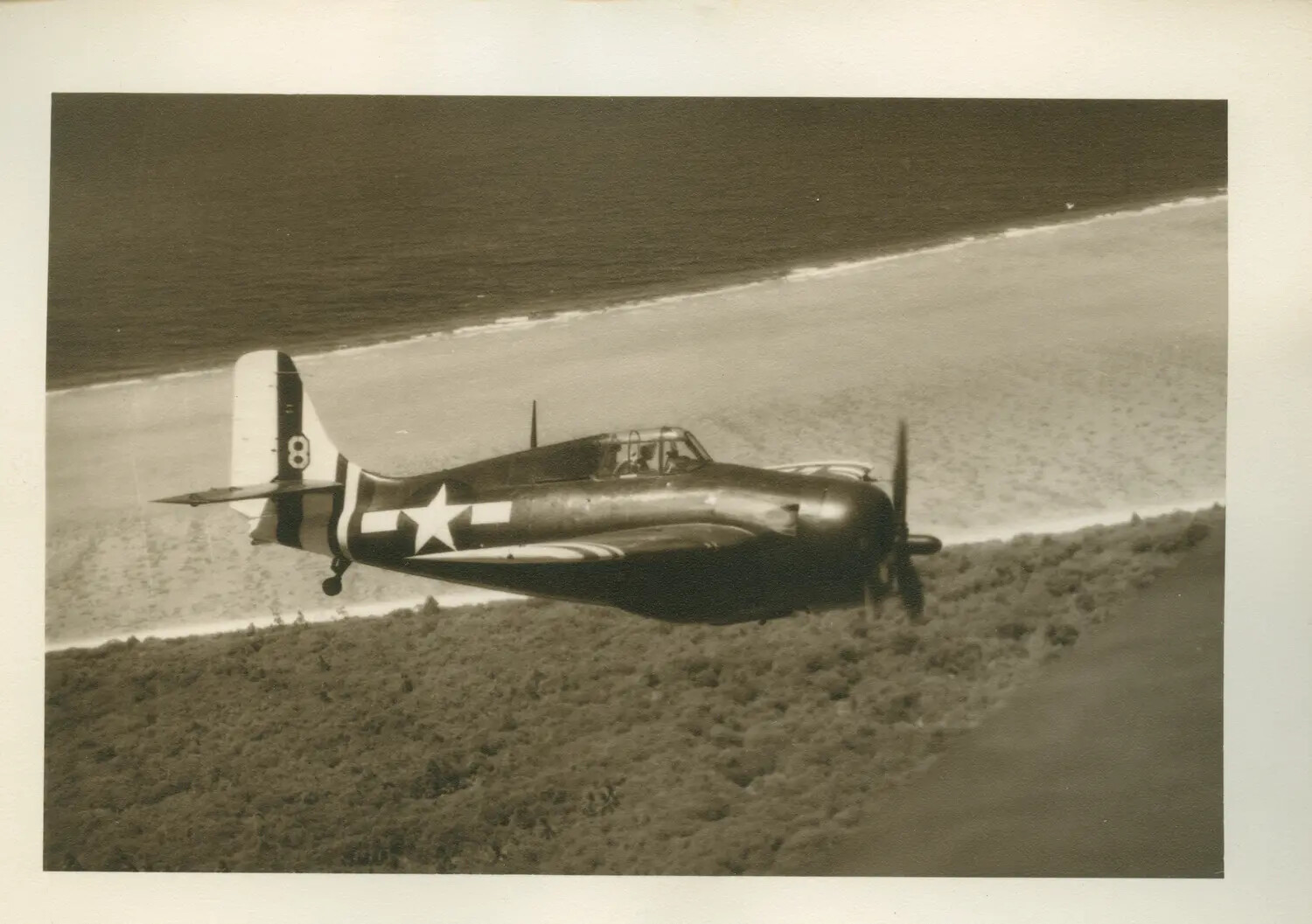 Grumman FM-2 Wildcat Fighter in Flight Along Coastline -- USS Petrof Bay (CVE-80) Collection