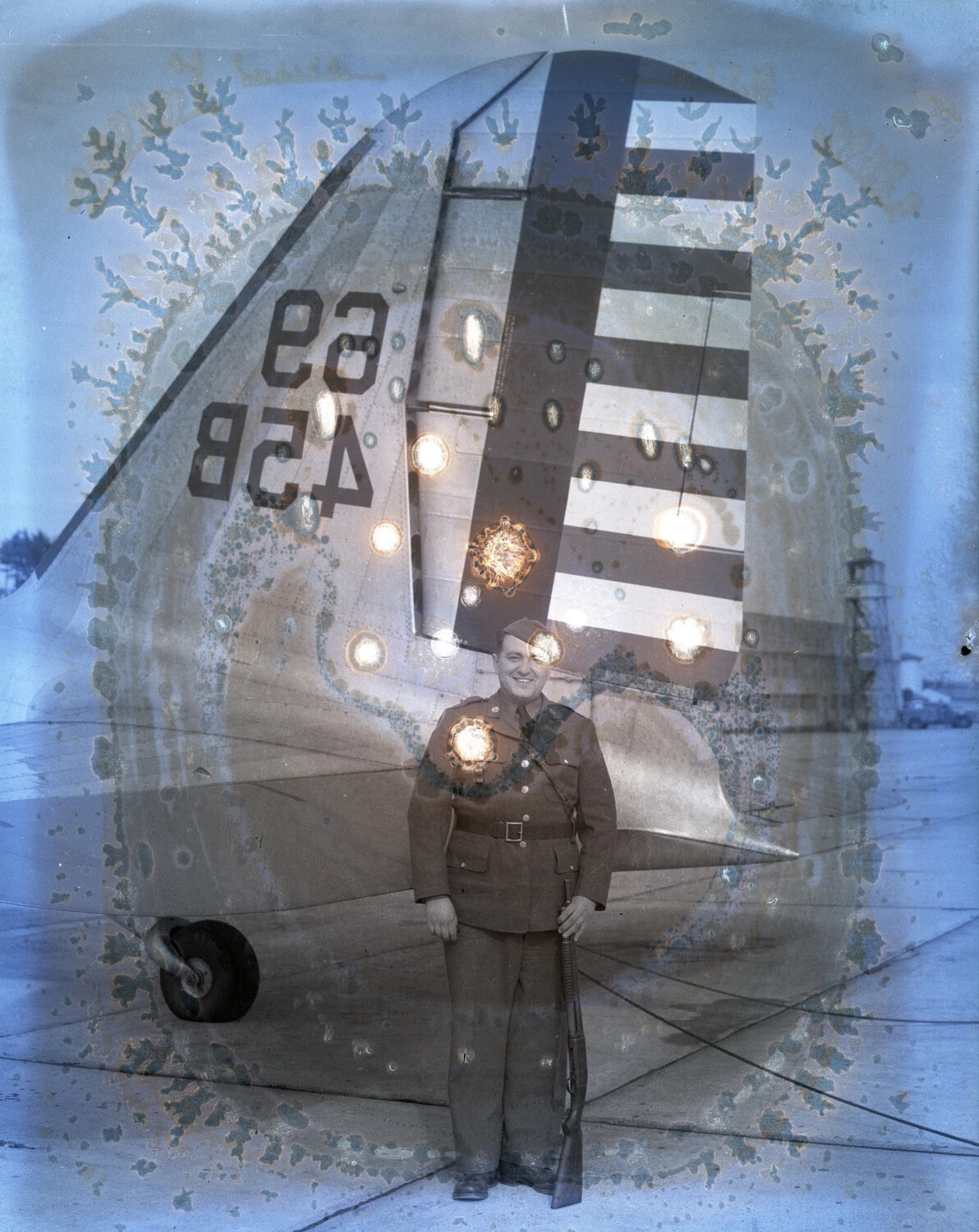 Damaged Negative: US Soldier Posing with Rifle Before Aircraft Tail with Invasion Stripes, WWII