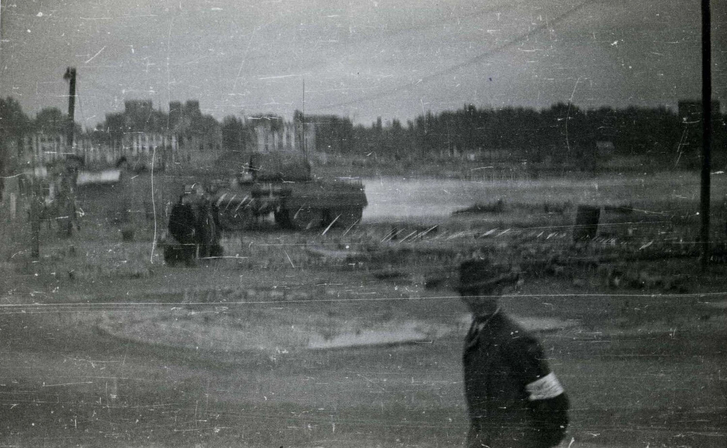 Civilian with Armband and Armored Vehicle in Damaged Townscape, 101st Airborne Division Collection (WWII, likely Netherlands, 1944)