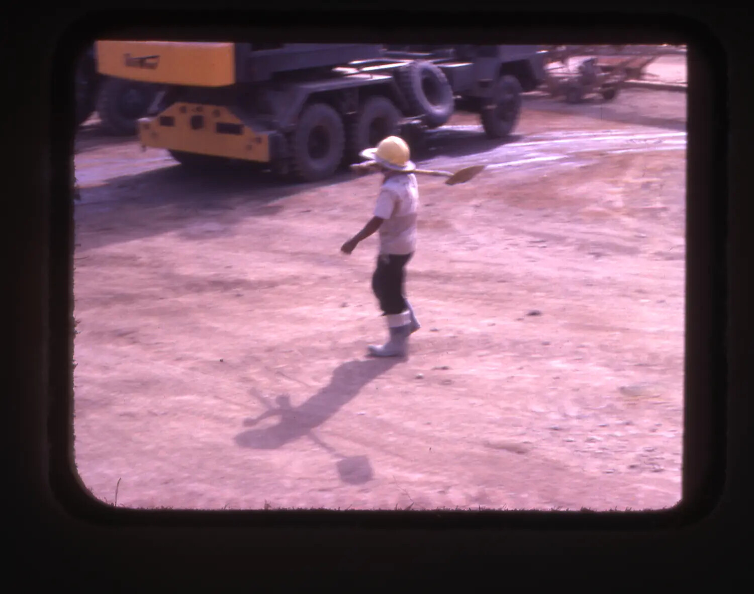 Vietnamese Laborer Carrying Shovel Past Construction Equipment, Cam Ranh Bay, Vietnam