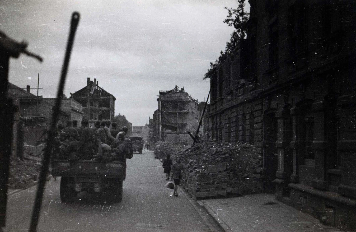 U.S. Troop Truck Passing Through Bomb-Damaged City Street, WWII European Theater