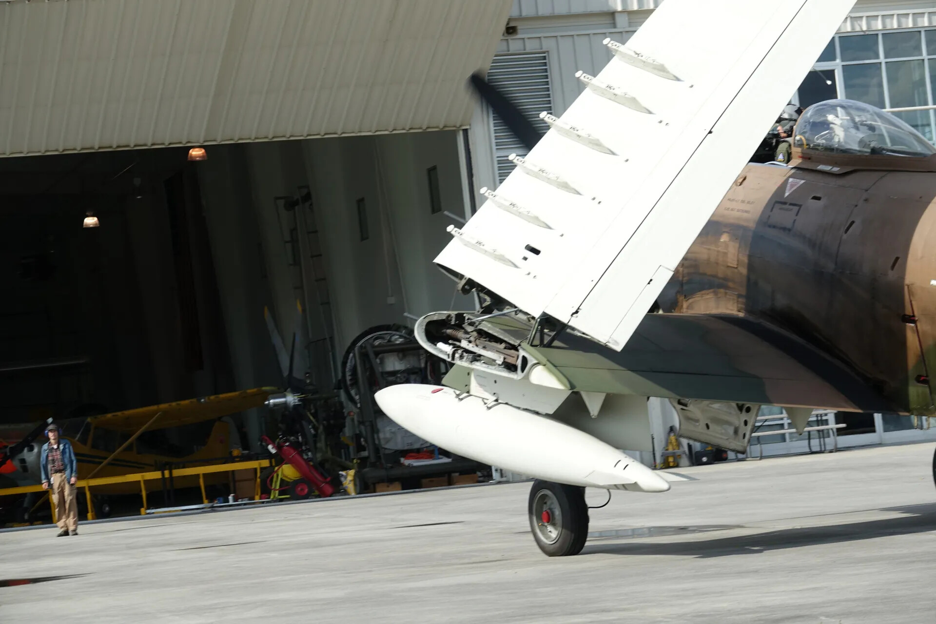 Camouflaged Warbird with Wing Raised, Exposing Gun Bay and Drop Tank, Air Show Maintenance Display, May 2019