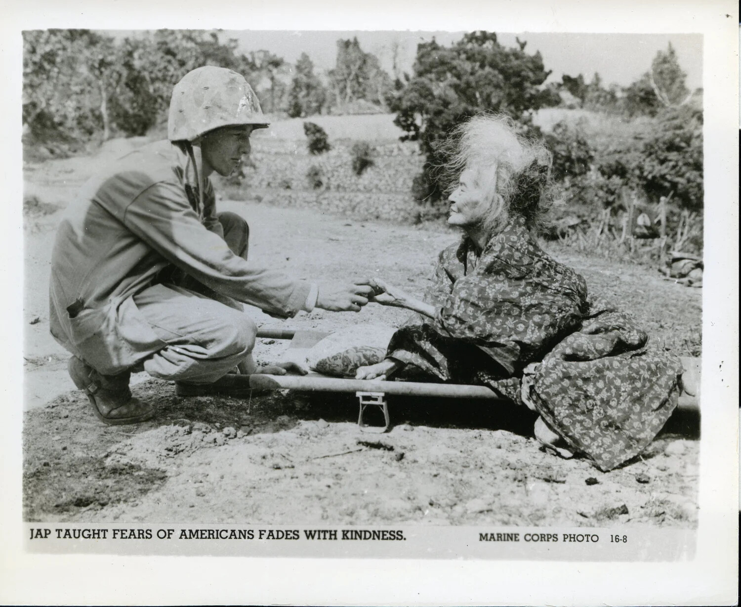 Marine Corps Official Photograph: U.S. Marine Assists Elderly Okinawan Woman on Stretcher, Battle of Okinawa, 1945