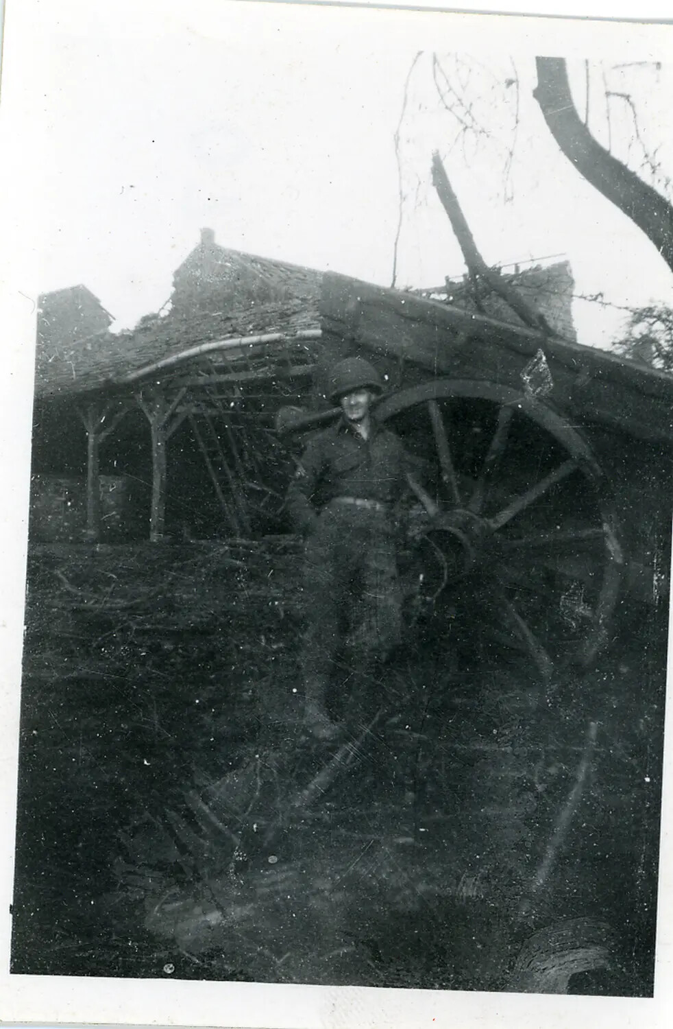 U.S. Army Soldier Beside a Wagon Wheel at a War-Damaged Rural Building, European Theater, WWII (circa 1944-1945)