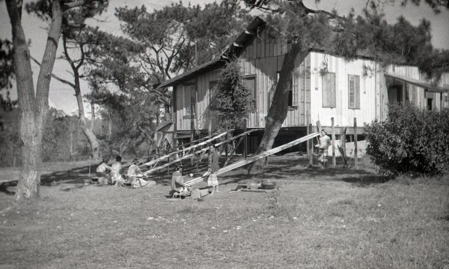 Filipino Civilians Weaving Textiles Near a Wooden Dwelling, Luzon, Philippines, WWII Era
