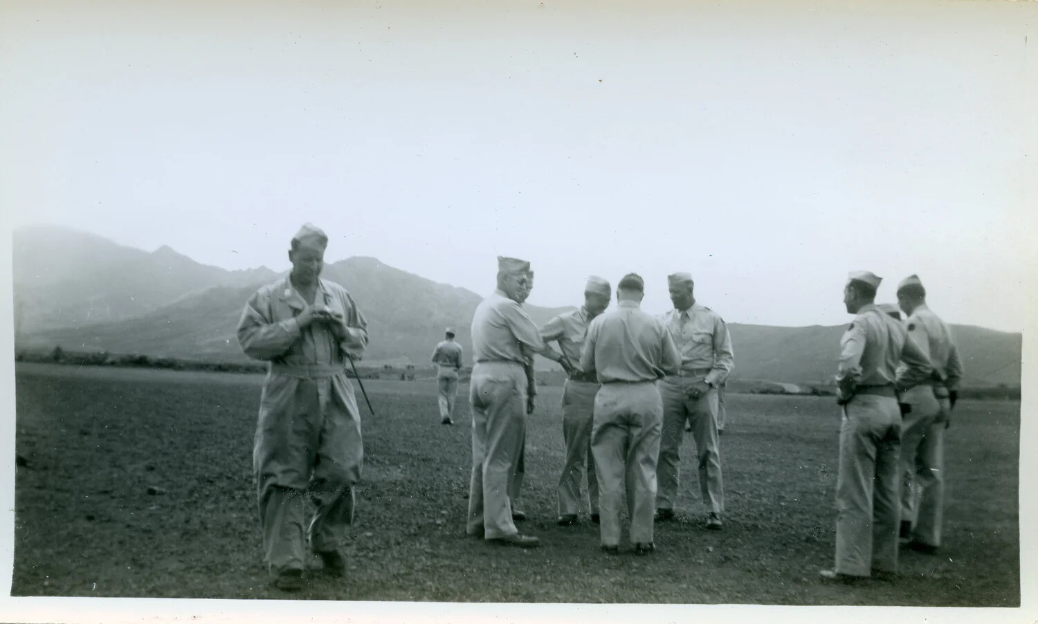 Servicemen Conversing in an Open Field with Mountains Beyond