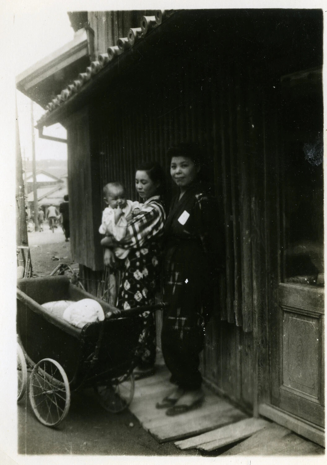 Japanese Mother, Child, and Companion in a Residential Doorway