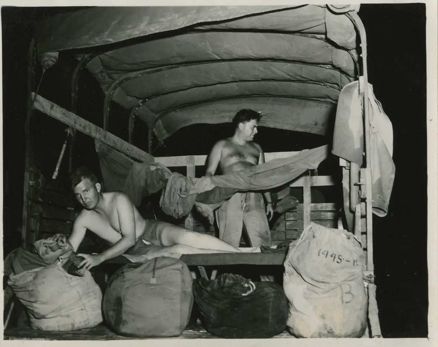 Servicemen Amid Stowed Gear Inside Truck Bed at Night, 312th Bombardment Group, November 1944