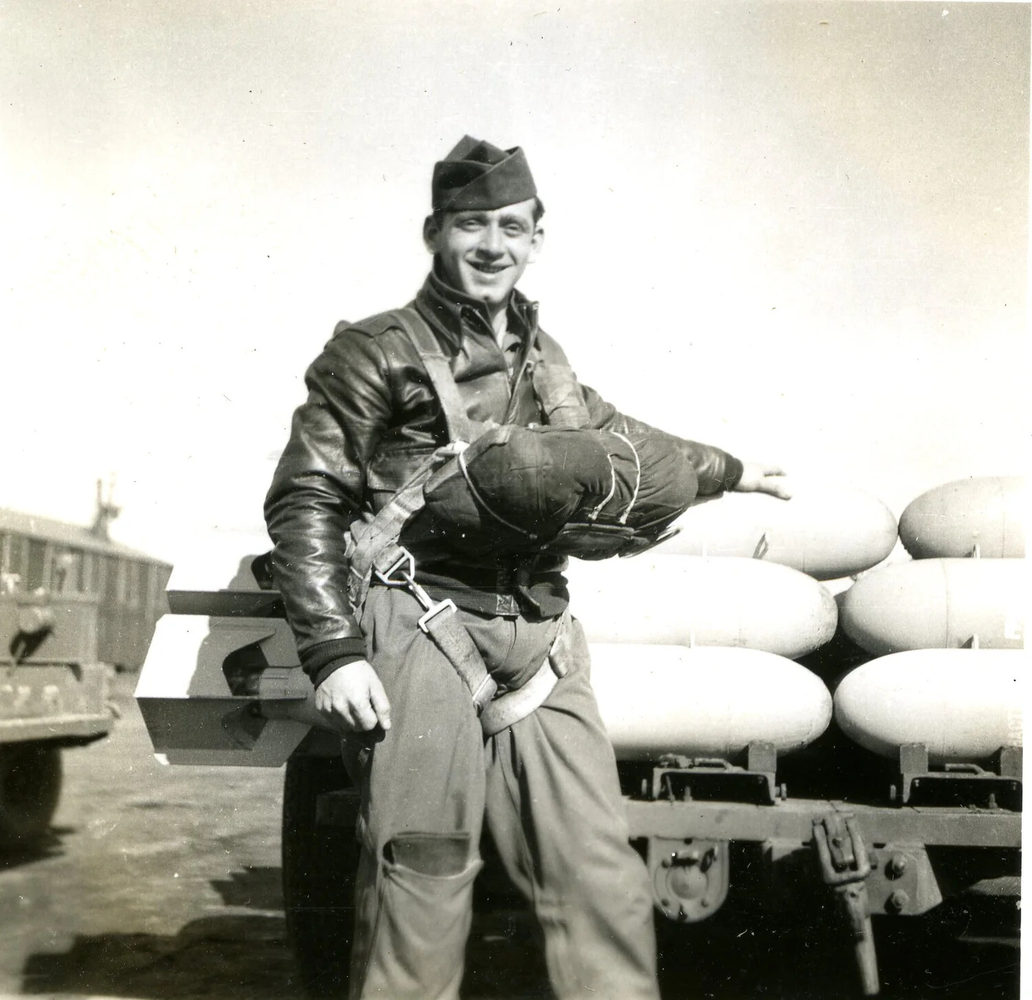 Aircrewman with Parachute Harness Beside Bomb Trailer