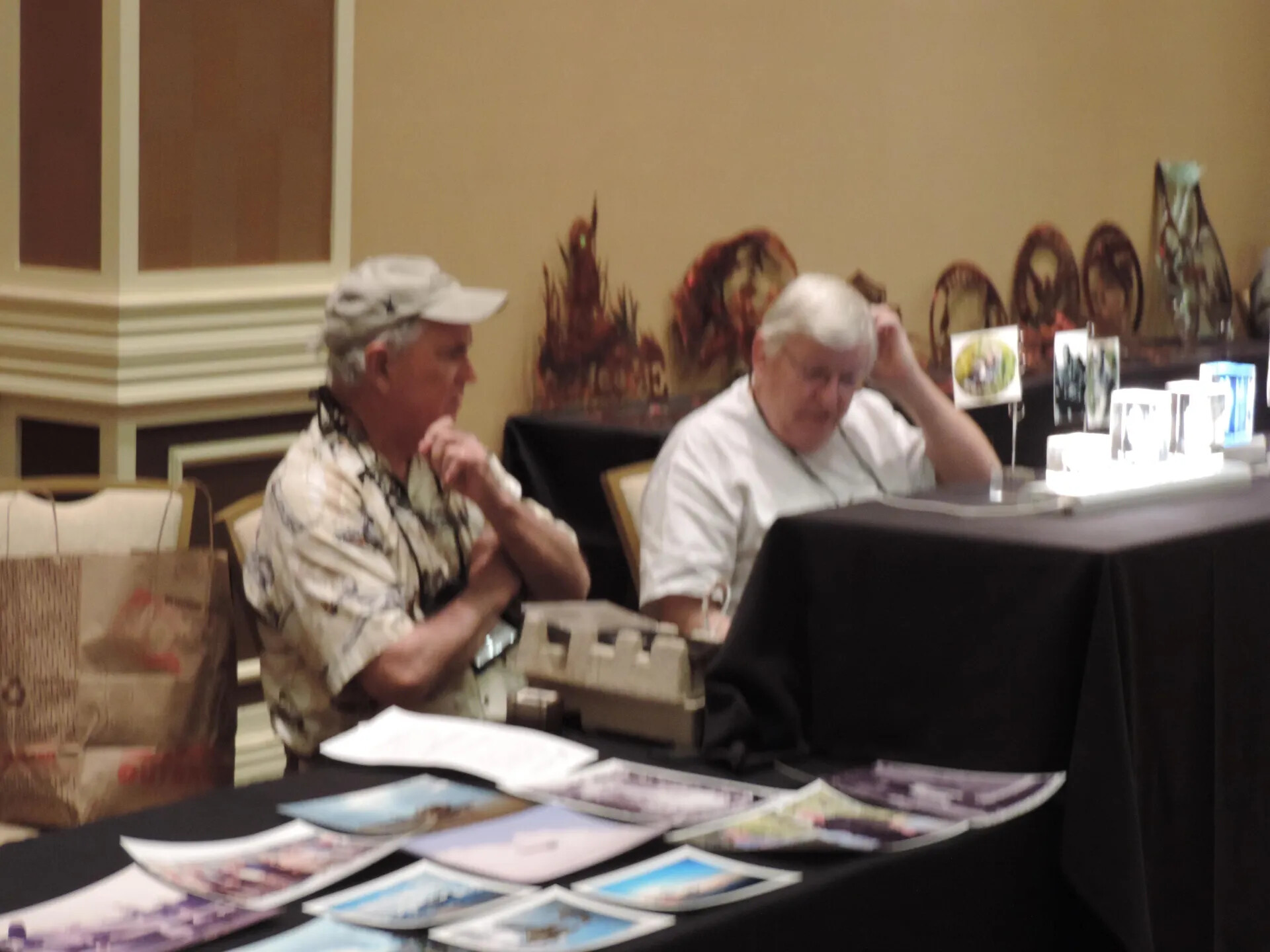 Two Attendees Behind a Table of Photographic Prints, Special Operations Association Reunion, Las Vegas, 2013 (Soft-Focus Exposure)