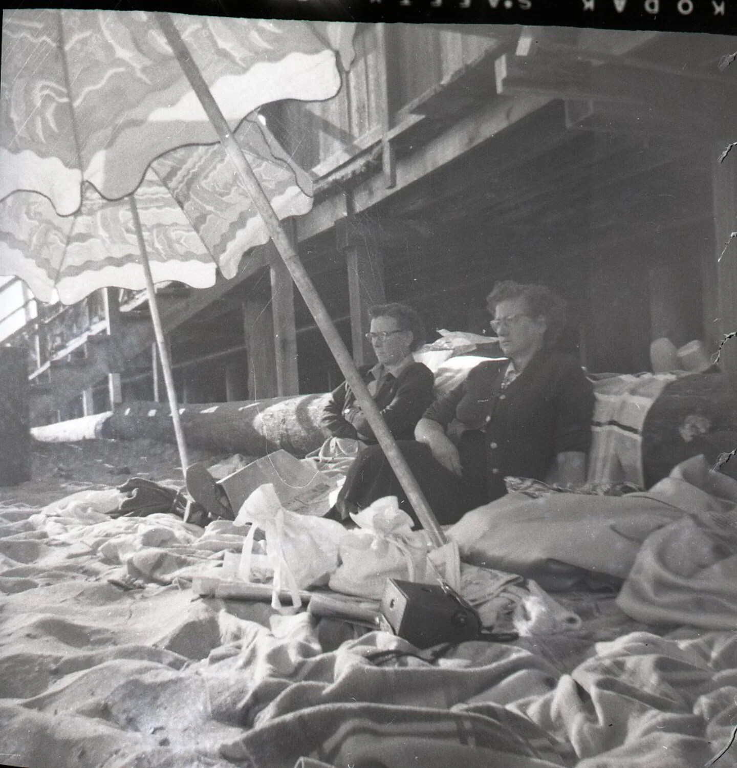 Two Women Seated on Beach Beneath Umbrella and Pier, Kelley Family Album