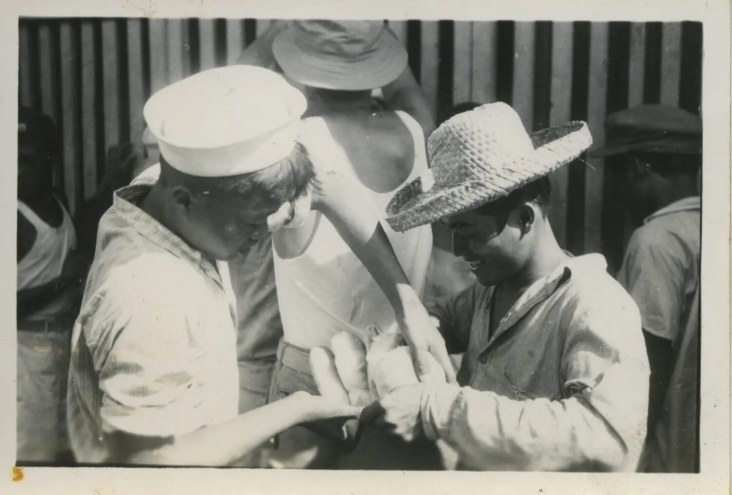 Sailor and Local Men Examining an Item Together, Pacific Theater