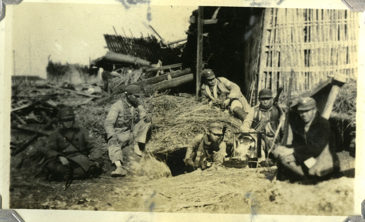 Soldiers Resting Around an Open Fire Amid Wreckage, c. 1930s